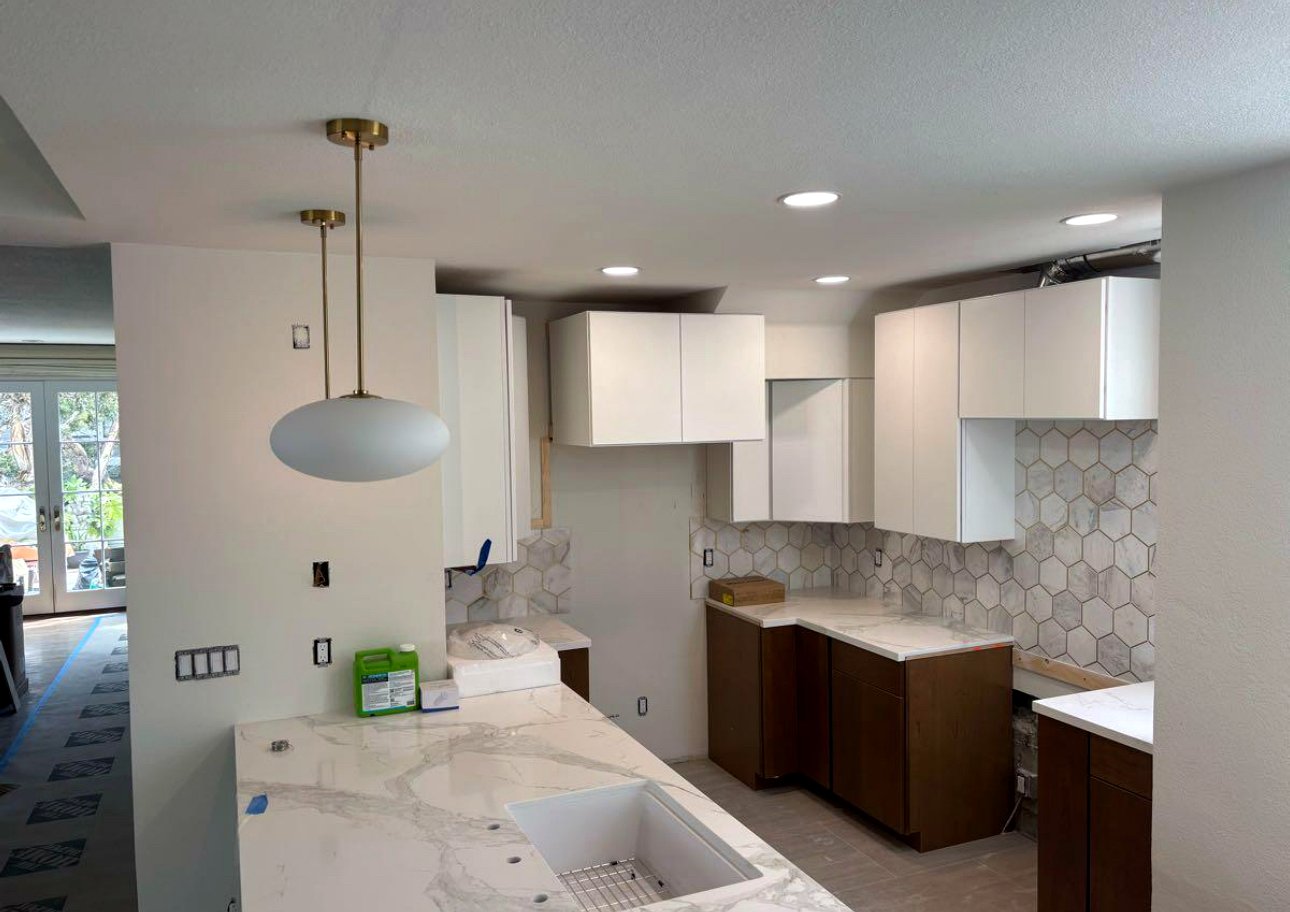 Modern kitchen with brass pendant lights and recessed cans